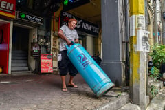 A man carrying LPG tanks for a restaurant