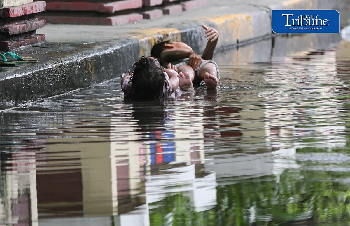 (July 25 2026) Two children turned the water collected from the heavy rain along Edsa on Saturday afternoon into a swimming pool. Photo/Analy Labor