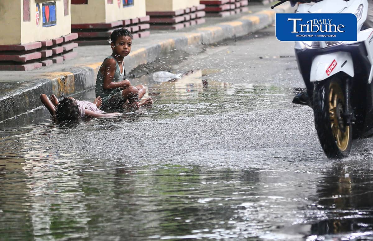 (July 25 2026) Two children turned the water collected from the heavy rain along Edsa on Saturday afternoon into a swimming pool. Photo/Analy Labor