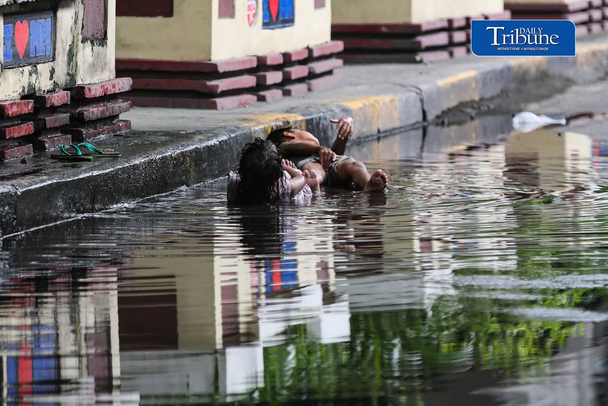 (July 25 2026) Two children turned the water collected from the heavy rain along Edsa on Saturday afternoon into a swimming pool. Photo/Analy Labor