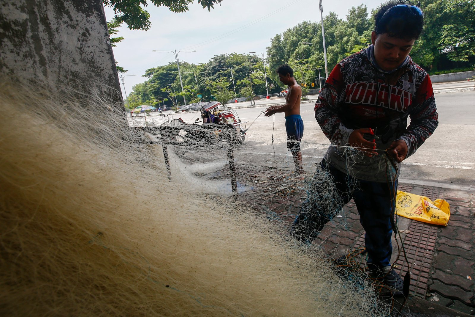 Fishermen repair a fishing net at Pescador Park in Navotas City on 30 July 2026 as they prepare for their next fishing trip following the full moon, a period when many local fishermen say they avoid going to sea because catches are often lower. The group is calling on President Ferdinand Marcos Jr. to increase fuel subsidies for fishermen, saying the current assistance is insufficient.