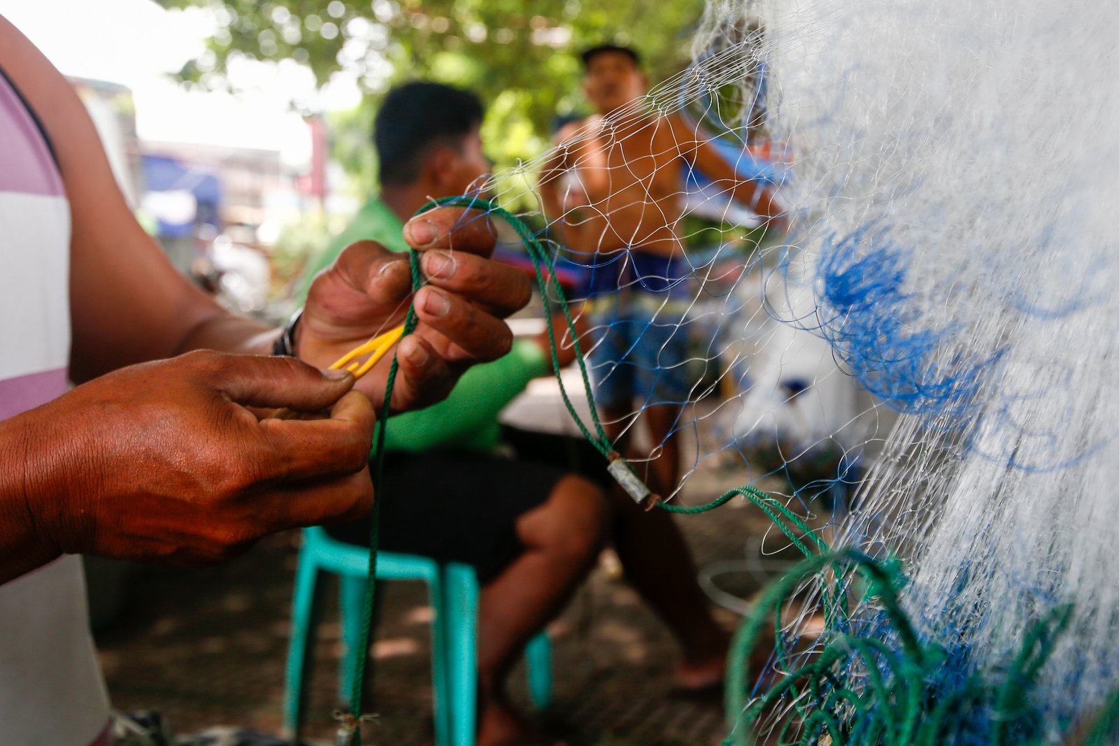 Fishermen repair a fishing net at Pescador Park in Navotas City on 30 July 2026 as they prepare for their next fishing trip following the full moon, a period when many local fishermen say they avoid going to sea because catches are often lower. The group is calling on President Ferdinand Marcos Jr. to increase fuel subsidies for fishermen, saying the current assistance is insufficient.
