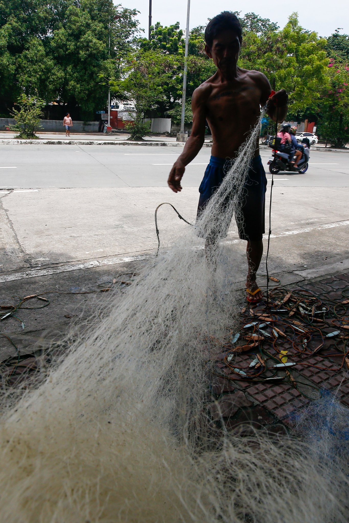 Fishermen repair a fishing net at Pescador Park in Navotas City on 30 July 2026 as they prepare for their next fishing trip following the full moon, a period when many local fishermen say they avoid going to sea because catches are often lower. The group is calling on President Ferdinand Marcos Jr. to increase fuel subsidies for fishermen, saying the current assistance is insufficient.