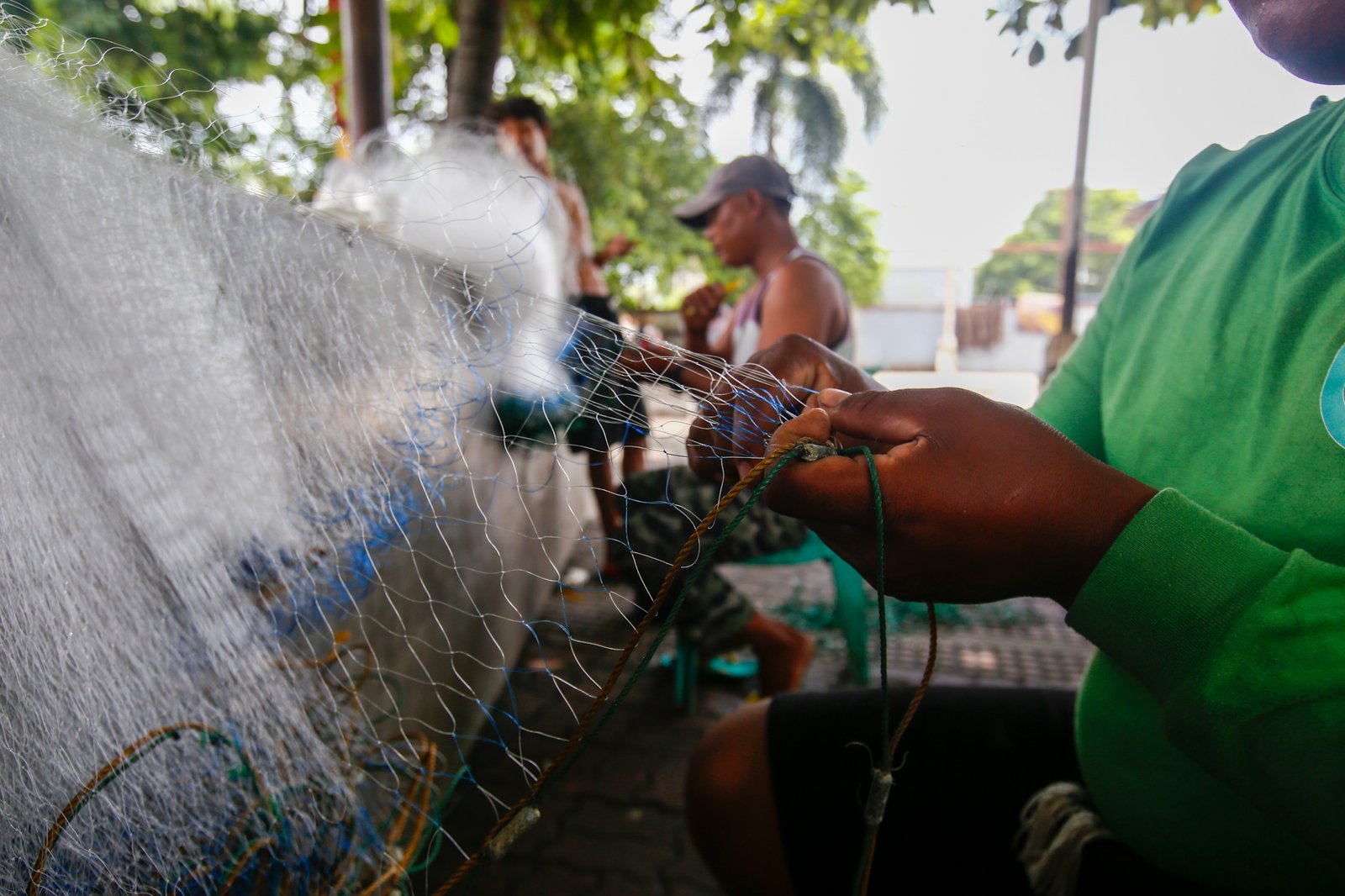 Fishermen repair a fishing net at Pescador Park in Navotas City on 30 July 2026 as they prepare for their next fishing trip following the full moon, a period when many local fishermen say they avoid going to sea because catches are often lower. The group is calling on President Ferdinand Marcos Jr. to increase fuel subsidies for fishermen, saying the current assistance is insufficient.