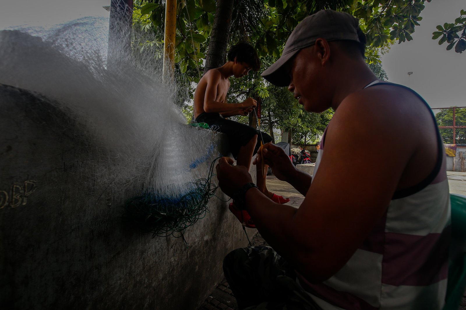 Fishermen repair a fishing net at Pescador Park in Navotas City on 30 July 2026 as they prepare for their next fishing trip following the full moon, a period when many local fishermen say they avoid going to sea because catches are often lower. The group is calling on President Ferdinand Marcos Jr. to increase fuel subsidies for fishermen, saying the current assistance is insufficient.