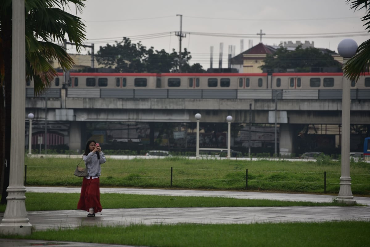 Visitors stroll around Rizal Park despite rain