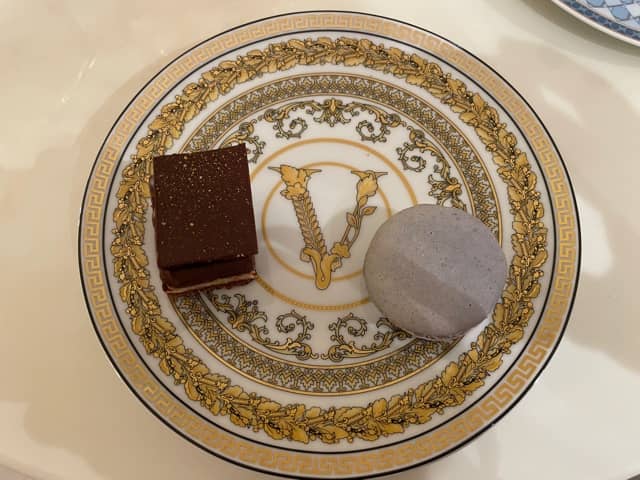 A chocolate cake slice and ube macaron on a Versace plate.