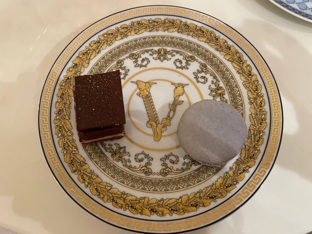 A chocolate cake slice and ube macaron on a Versace plate.