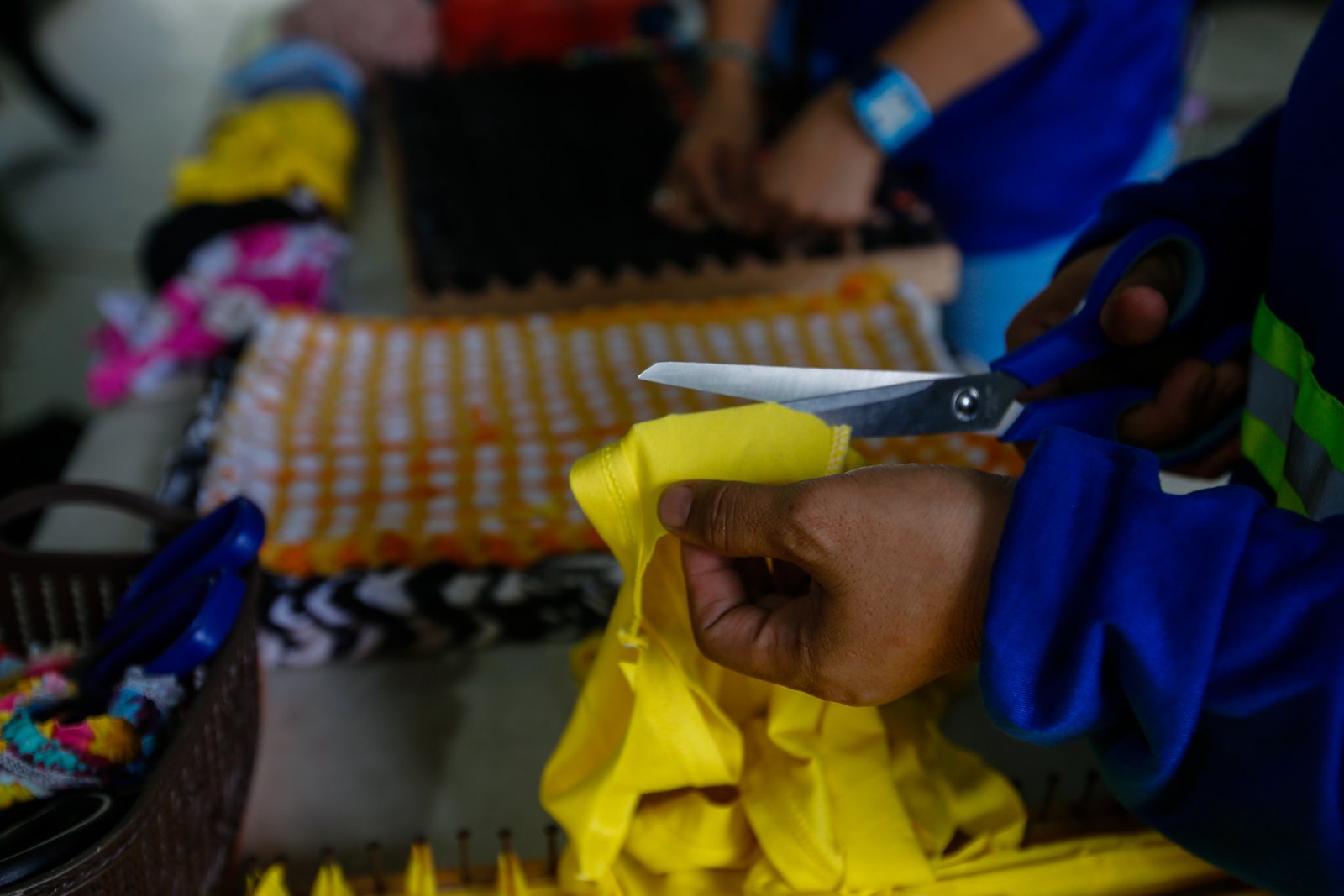Mary Ann Doble, Loida Domingo and Marilou Reposo transform worn-out T-shirts into rags and mats at a materials recovery facility in Manila on 4 August 2026. The three women learned the upcycling craft through online tutorials.