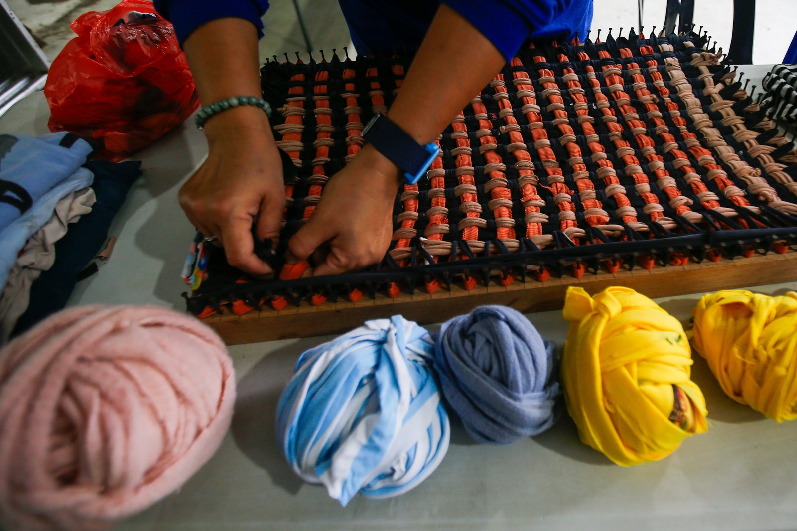 Mary Ann Doble, Loida Domingo and Marilou Reposo transform worn-out T-shirts into rags and mats at a materials recovery facility in Manila on 4 August 2026. The three women learned the upcycling craft through online tutorials.
