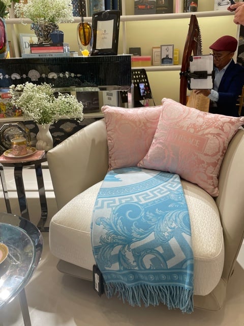 A harpist plays behind this sofa accentuated with Versace throw pillows and quilt.