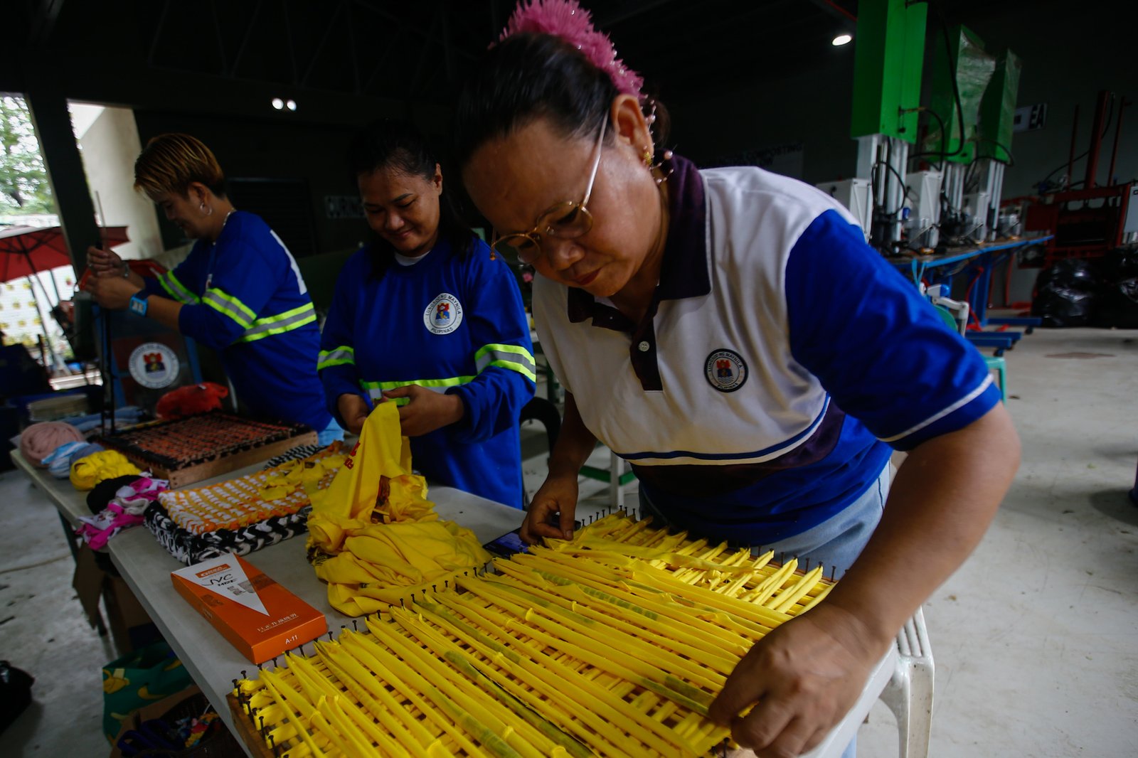Mary Ann Doble, Loida Domingo and Marilou Reposo transform worn-out T-shirts into rags and mats at a materials recovery facility in Manila on 4 August 2026. The three women learned the upcycling craft through online tutorials.