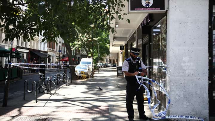 A Police Community Support Officers (PCSO) removes police tape from a cordon, at Endell road in covent garden, central London on August 5, 2026.
A woman was arrested after four men were stabbed in Covent Garden, a busy area of central London popular with tourists, the Metropolitan Police said on August 5. The victims were four men aged 34, 39, 42 and 52, police said, adding that it was "believed to be a mental health related incident" based on the early stages of the probe.