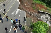 Local officials and residents stand near caution tape inspecting a massive section of the Davao-Bukidnon Highway that collapsed near Purok 12 Falls in Barangay Buda, Davao City. A major landslide triggered by relentless southwest monsoon rains caused the road failure, prompting the Department of Public Works and Highways to declare the vital transport artery impassable while assessment and repairs get underway.