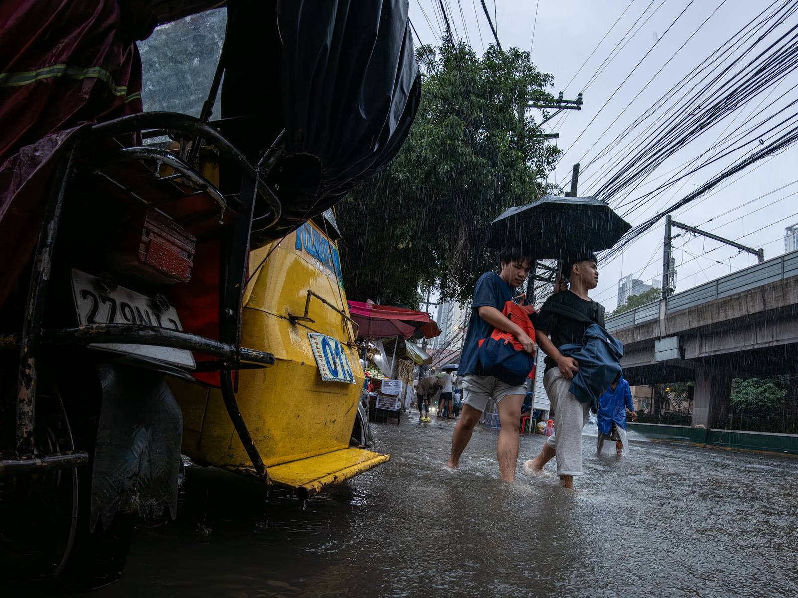 Motorists and commuters wade through gutter-deep floodwaters at the corner of Taft Avenue and Escoda Street in Manila on August 8, 2026, after PAGASA issued an Orange Rainfall Warning over Metro Manila at 11:02 a.m.
