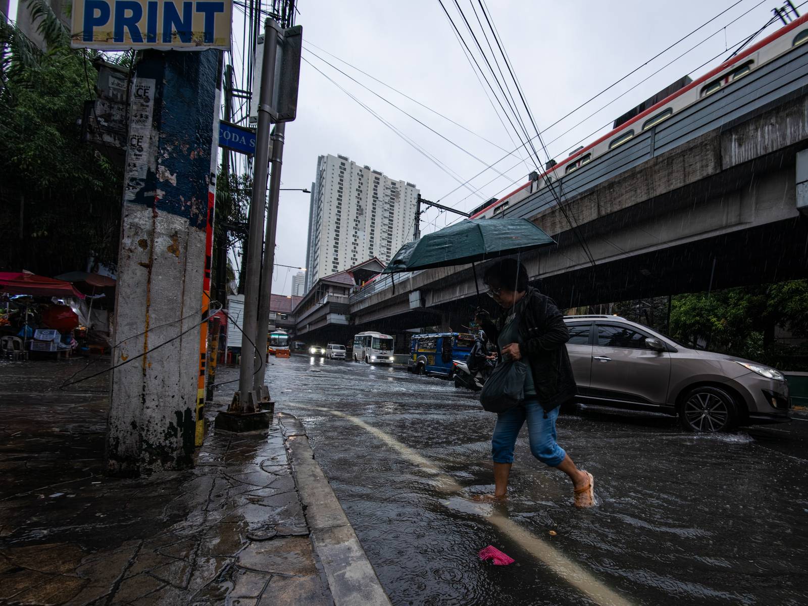Motorists and commuters wade through gutter-deep floodwaters at the corner of Taft Avenue and Escoda Street in Manila on August 8, 2026, after PAGASA issued an Orange Rainfall Warning over Metro Manila at 11:02 a.m.