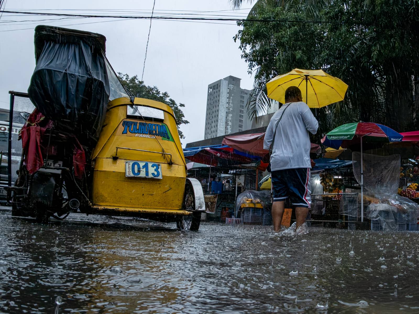 Motorists and commuters wade through gutter-deep floodwaters at the corner of Taft Avenue and Escoda Street in Manila on August 8, 2026, after PAGASA issued an Orange Rainfall Warning over Metro Manila at 11:02 a.m.