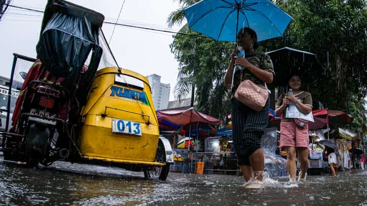 Motorists and commuters wade through gutter-deep floodwaters at the corner of Taft Avenue and Escoda Street in Manila on August 8, 2026, after PAGASA issued an Orange Rainfall Warning over Metro Manila at 11:02 a.m.