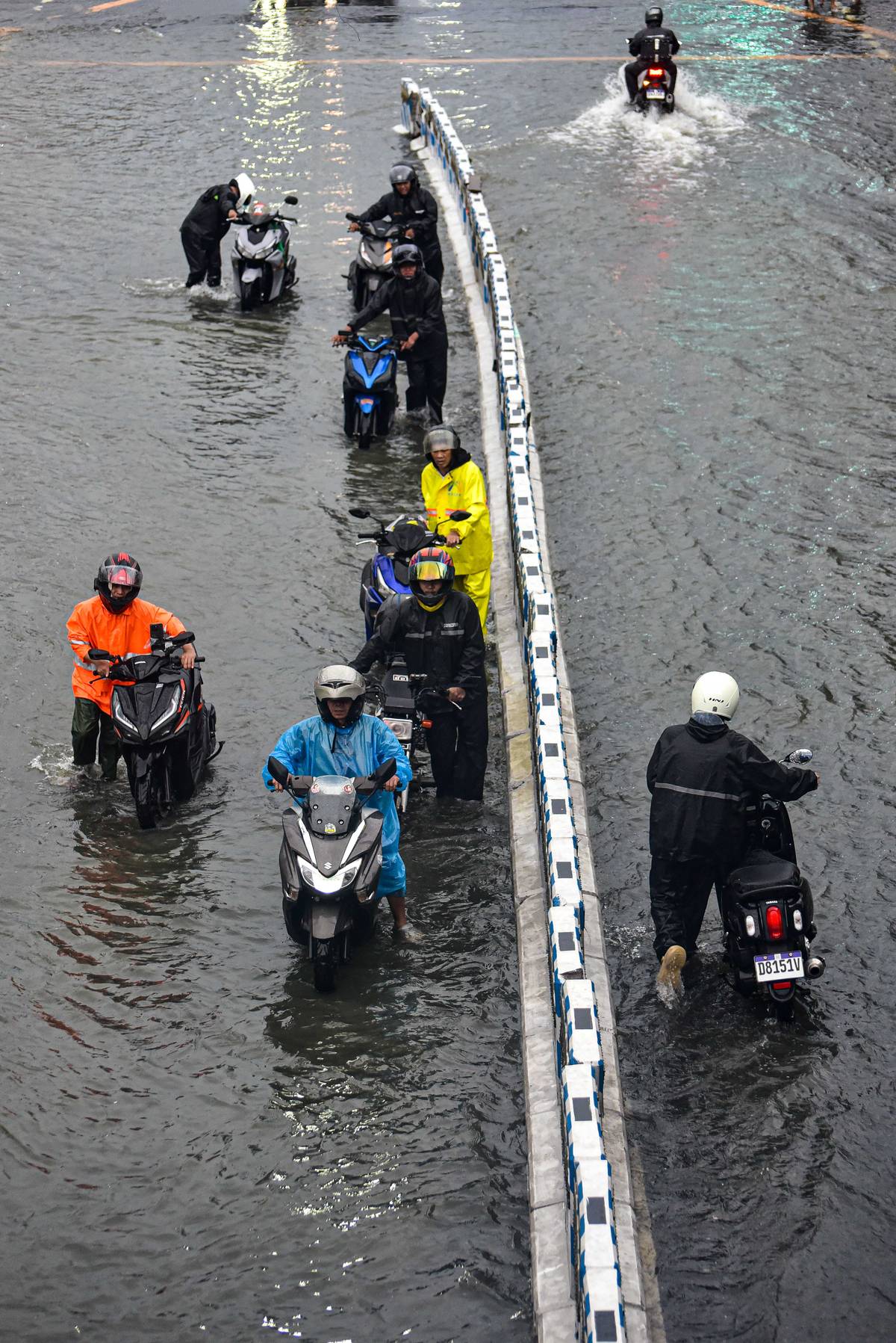 ‘Diskarte’ Motorcycle riders stick to the inner lanes, where floodwaters are generally shallower, as rains blanket Metro Manila.