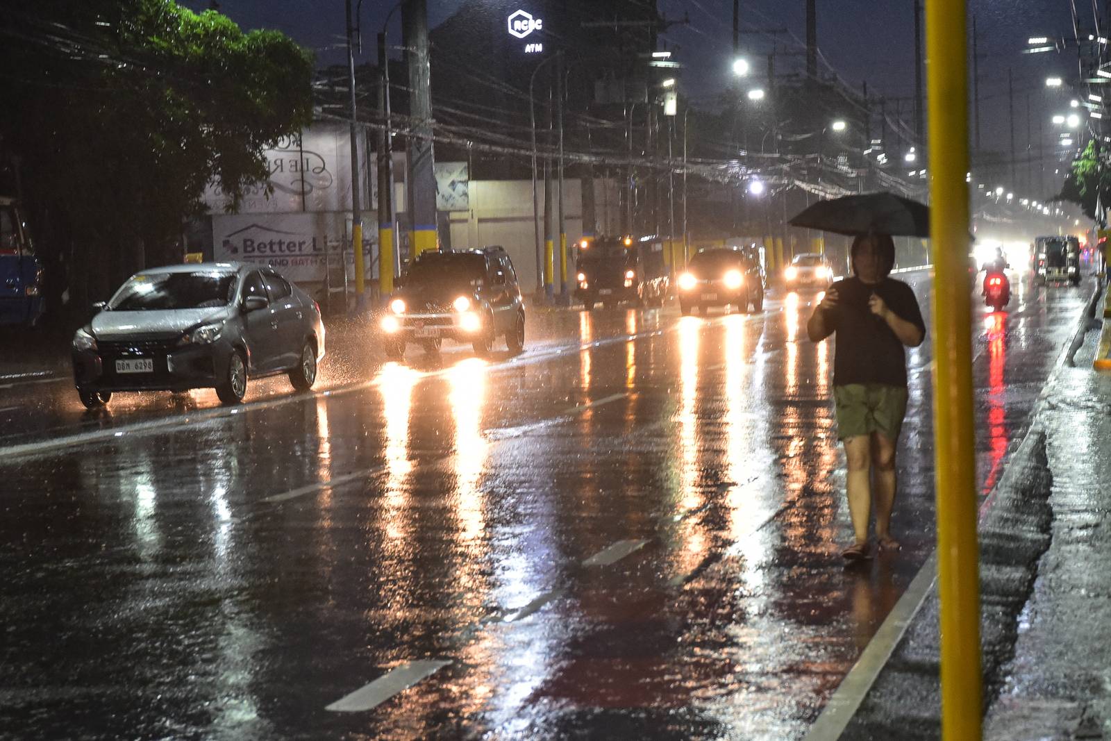 Motorists along Emilio Aguinaldo Highway use umbrellas as they brave heavy rainfall brought by the enhanced southwest monsoon, or habagat, on August 8. | Zedrich Xylak Madrid