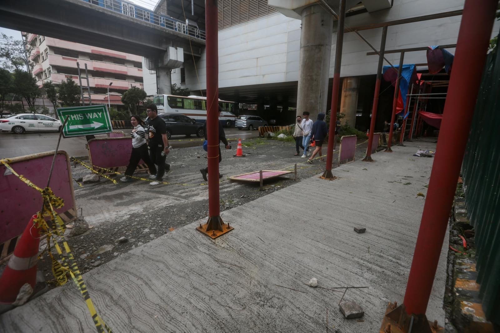 Pedestrians struggle to navigate a muddy, soil-covered road beneath a construction site leading to the MRT North Avenue station in Quezon City. | Aram Lascano