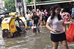 Pedestrians wade through a sea-like flood in Manila