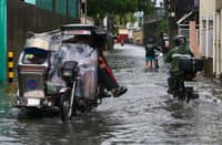 Residents and motorists wade through a flooded street in Parañaque City on Sunday, 9 August, as the southwest monsoon (Habagat) continues to bring rain across Metro Manila and other parts of the country.