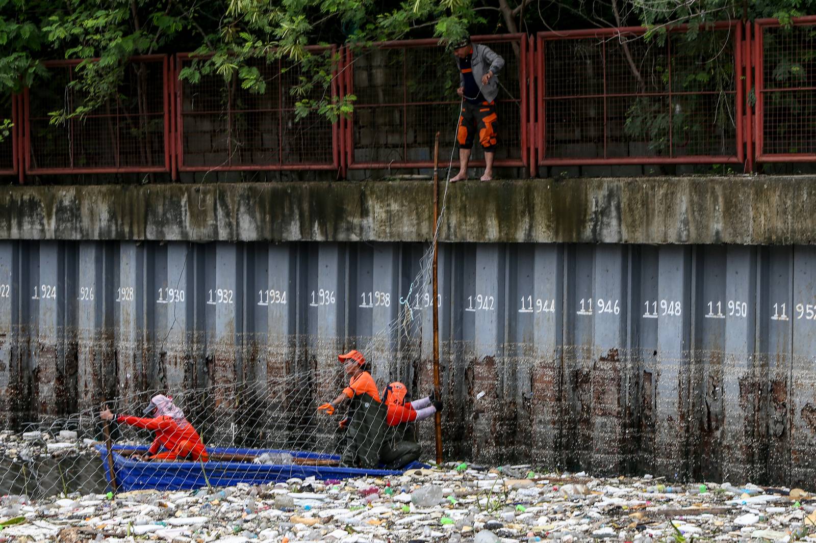 Personnel work through the rain to clear a massive buildup of garbage from the Redemptorist Water Channel in Parañaque City on Tuesday afternoon, 11 August. | Aram Lascano