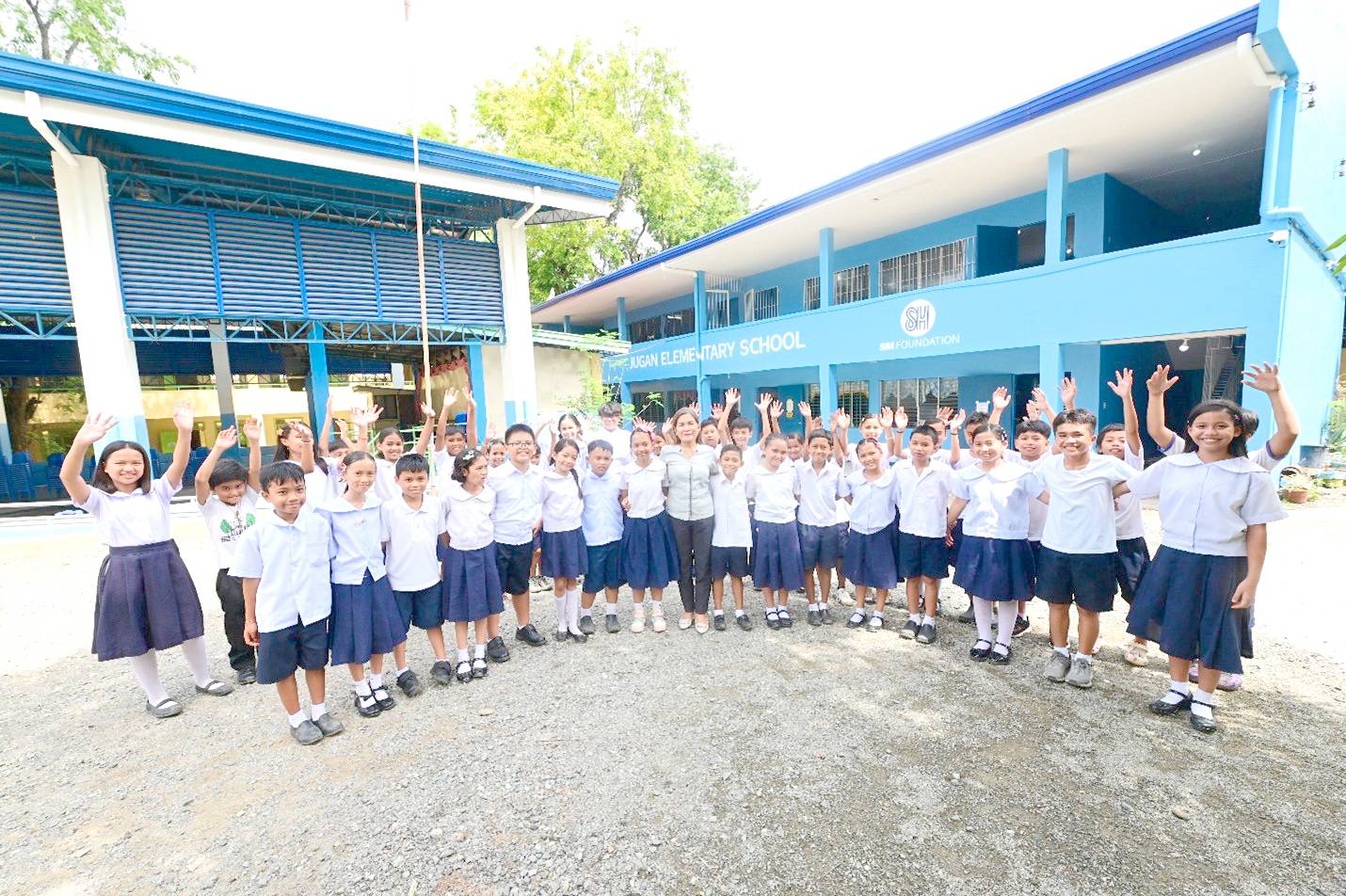 Principal Mafe Morales Baladjay (center) with some students in front of the newly rehabilitated two-story, four classroom building of Jugan ES.