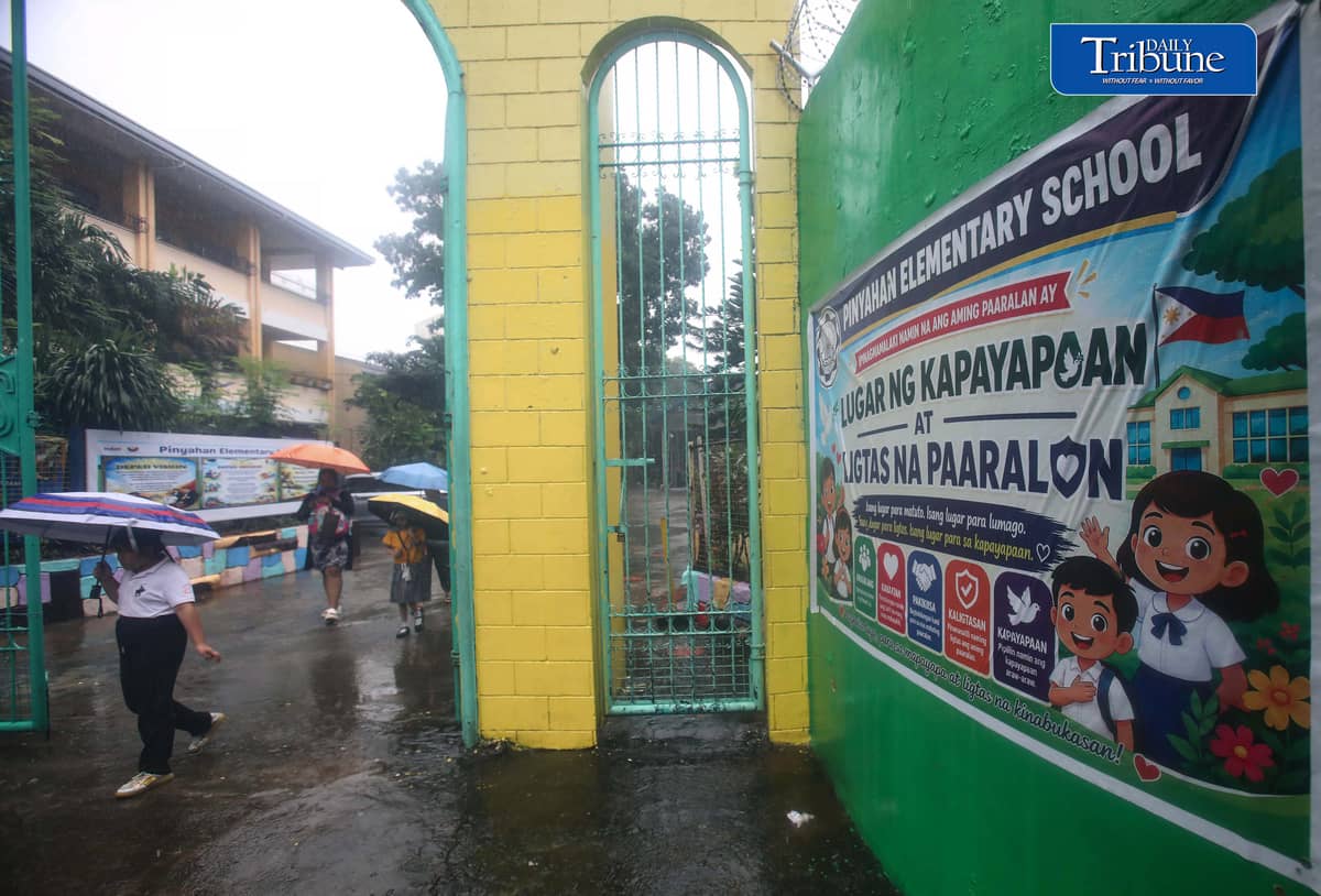 (August 14 2026) Students from Pinyahan elementary schools in Quezon City, accompanied by their guardian use umbrellas as they brave the rain on their way home after classes were suspended due to continuous rains brought by enhanced southwest monsoon on Friday, August 14, 2026. PAGASA said the rainy weather may persist into next week as a low pressure area could form inside the Philippine area of responsibility between Sunday and early next week, potentially enhancing the southwest monsoon. Photo/Analy Labor