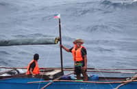 A Filipino fisher heads out under the flag in waters where simply making a living now carries the weight of sovereignty.