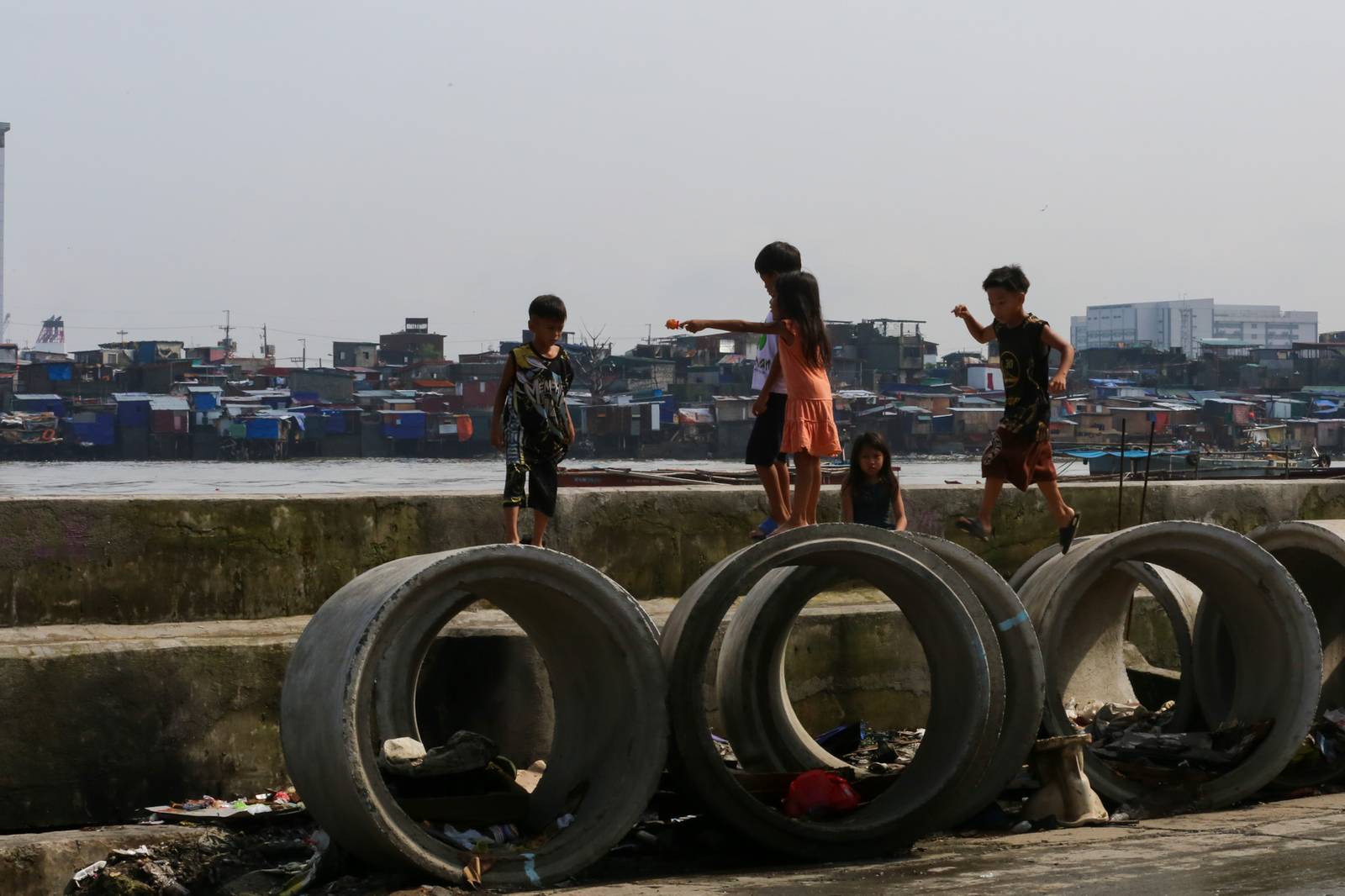 Children play on concrete culvert pipes intended for a drainage project in Baseco, Tondo, Manila, on 15 August 2026, as the skies begin to clear after weeks of rain brought by the southwest monsoon, or habagat.