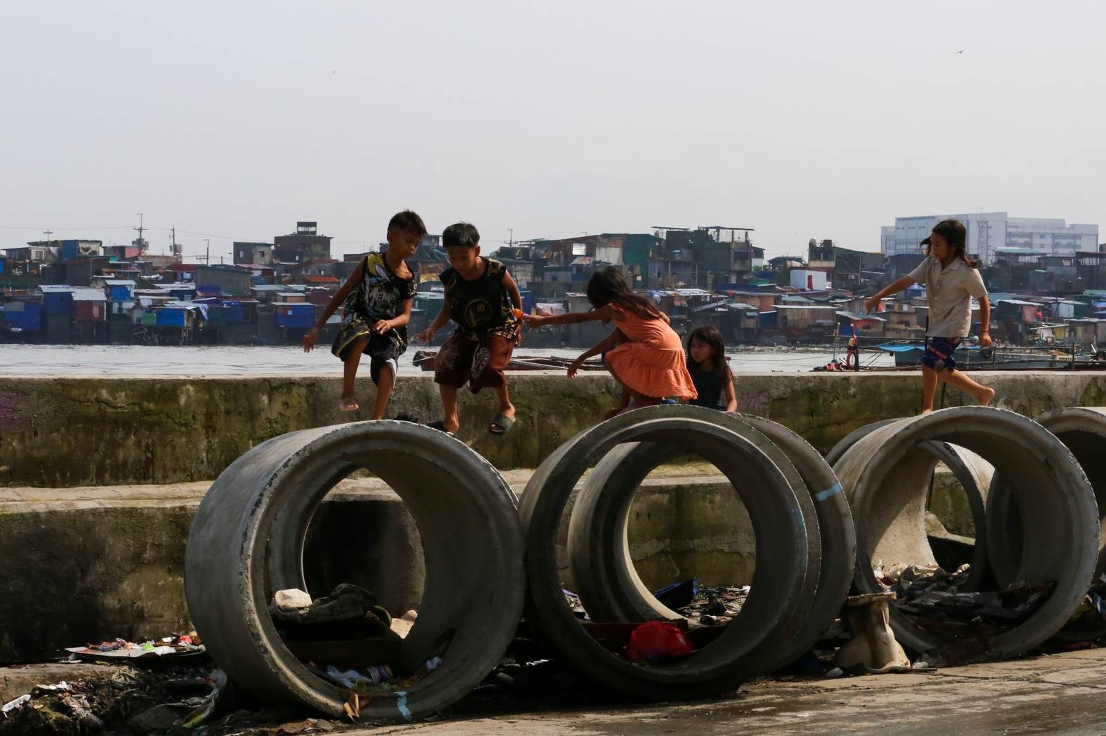 Children play on concrete culvert pipes intended for a drainage project in Baseco, Tondo, Manila, on 15 August 2026, as the skies begin to clear after weeks of rain brought by the southwest monsoon, or habagat.
