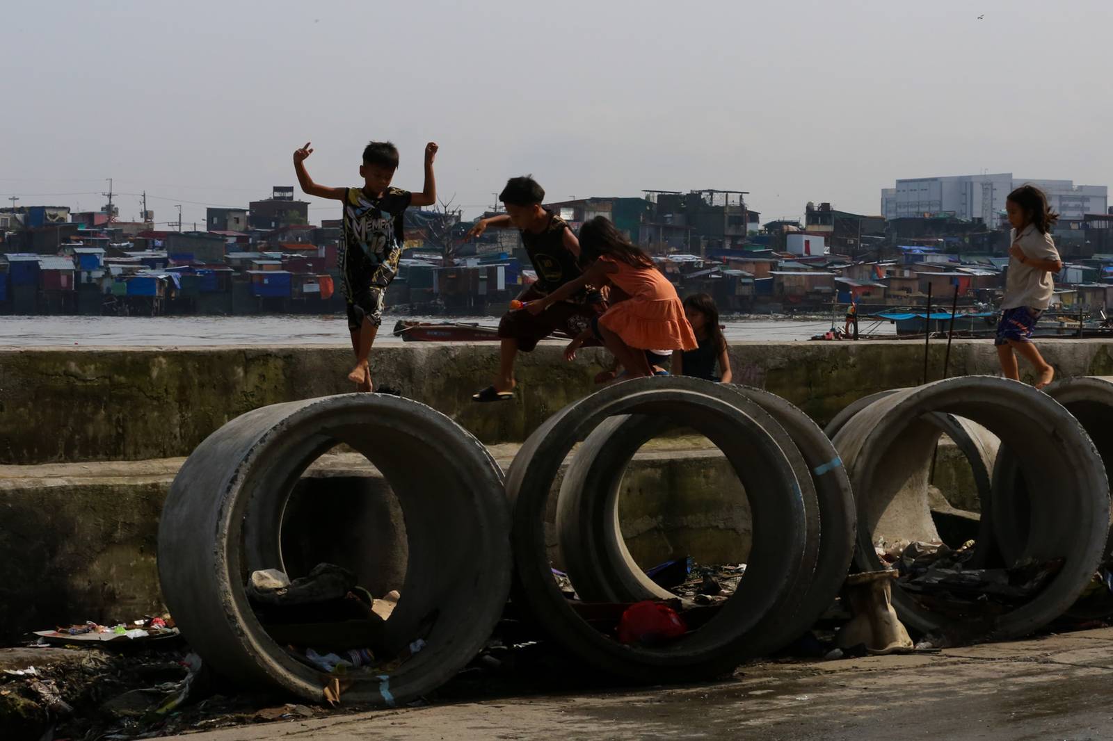 Children play on concrete culvert pipes intended for a drainage project in Baseco, Tondo, Manila, on 15 August 2026, as the skies begin to clear after weeks of rain brought by the southwest monsoon, or habagat.