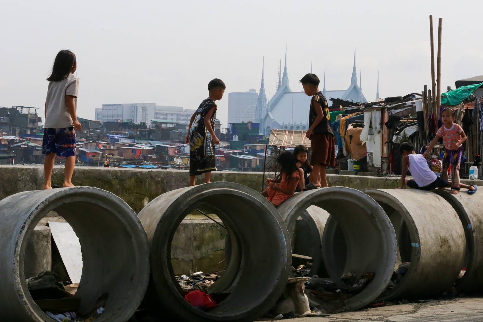 Children play on concrete culvert pipes intended for a drainage project in Baseco, Tondo, Manila, on 15 August 2026, as the skies begin to clear after weeks of rain brought by the southwest monsoon, or habagat.