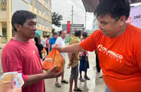 AN OMF volunteer hands a relief pack to a Bacoor resident on 14 August 2026.