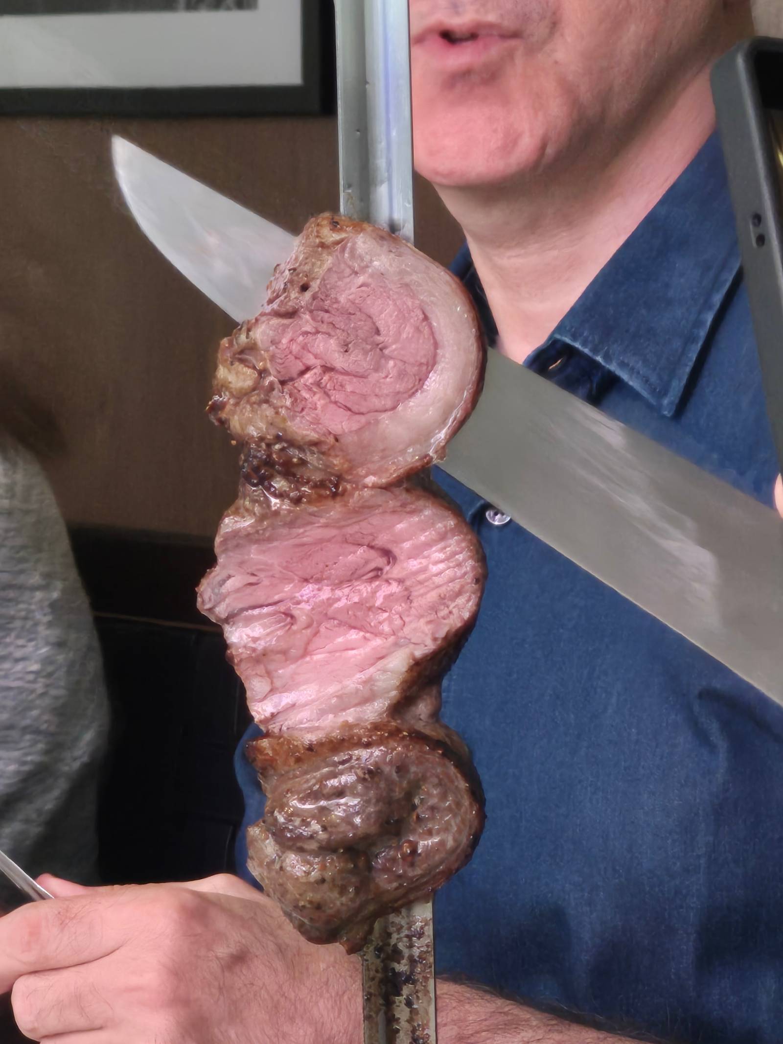A skewer of thick-cut, medium-rare prime beef seasoned with coarse salt, showcasing the core offering of traditional churrasco cuisine.