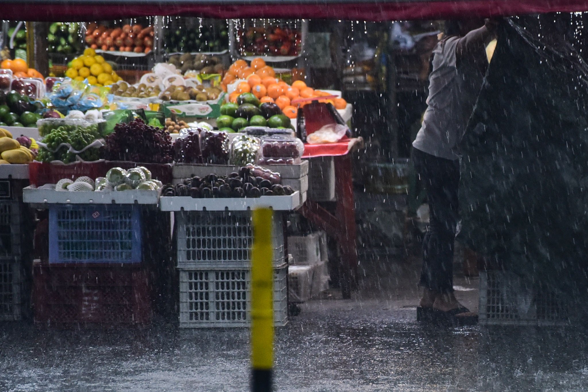 Woman covers her fresh goods amid heavy downpour
