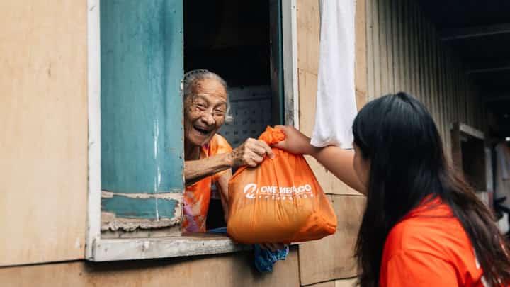 A MERALCO volunteer hands a relief pack to a resident of a flooded community.
