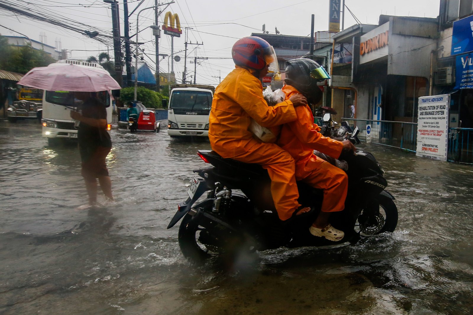 Motorists wade through gutter-deep floodwaters in Malabon City on 29 August 2026, as a signboard alerts the public to a traffic advisory for ongoing road and drainage system rehabilitation works that began on 06 April and are set to continue for 120 calendar days.