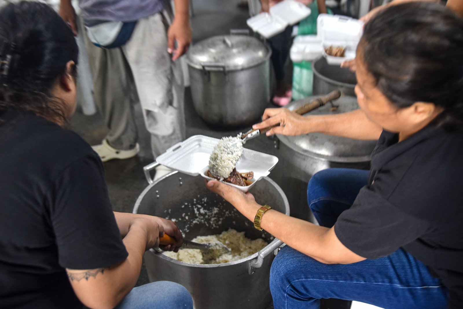 Families displaced by the effects of the southwest monsoon receive hot meals prepared by Manila Department of Social Welfare personnel at the Don Bosco Evacuation Center in Sta. Mesa, Manila, on August 30. The center is sheltering 515 evacuees. l Zedrich Xylak Madrid