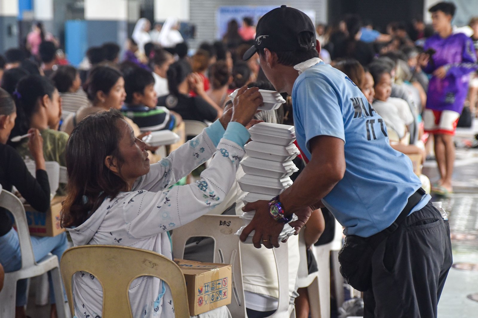 Families displaced by the effects of the southwest monsoon receive hot meals prepared by Manila Department of Social Welfare personnel at the Don Bosco Evacuation Center in Sta. Mesa, Manila, on August 30. The center is sheltering 515 evacuees. l Zedrich Xylak Madrid