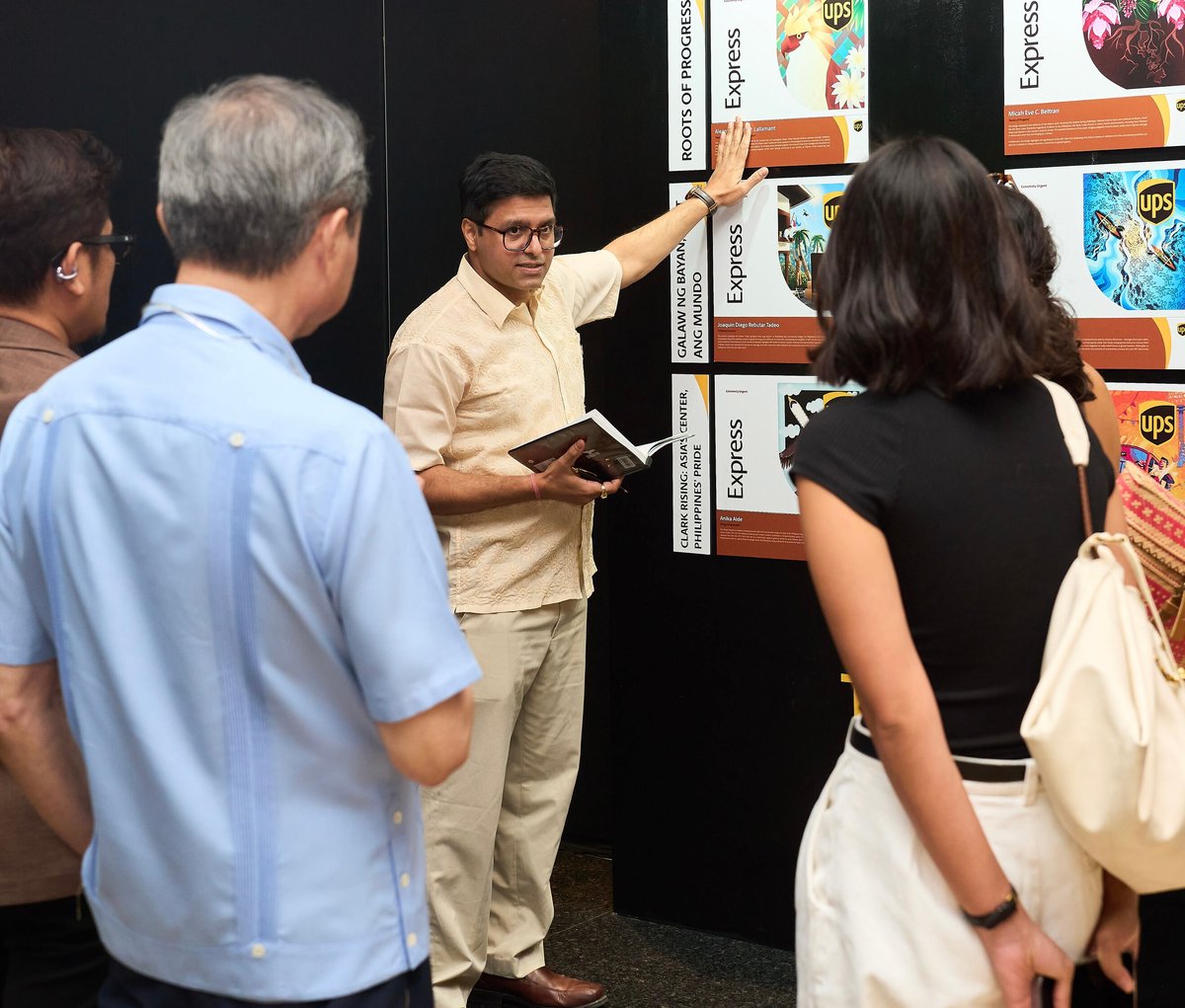 UPS Philippines Vibhav Varshney giving guests a tour of the student artwork exhibit.
