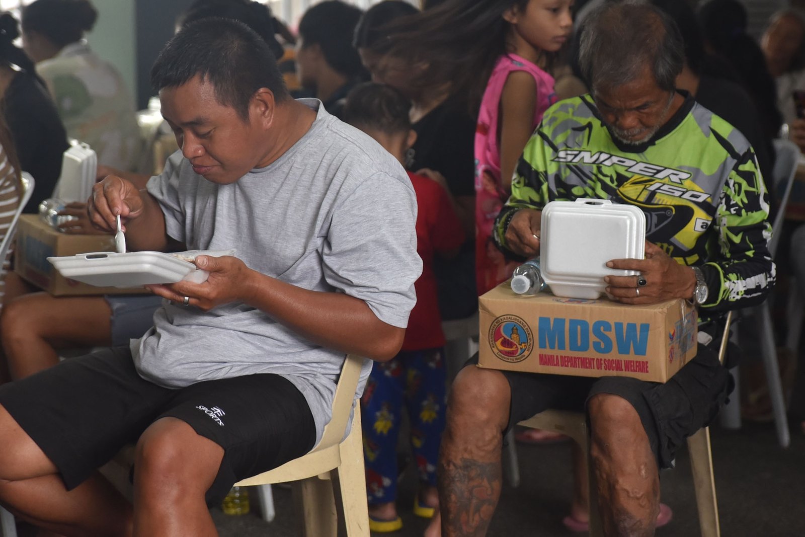 Families displaced by the effects of the southwest monsoon receive hot meals prepared by Manila Department of Social Welfare personnel at the Don Bosco Evacuation Center in Sta. Mesa, Manila, on August 30. The center is sheltering 515 evacuees. l Zedrich Xylak Madrid