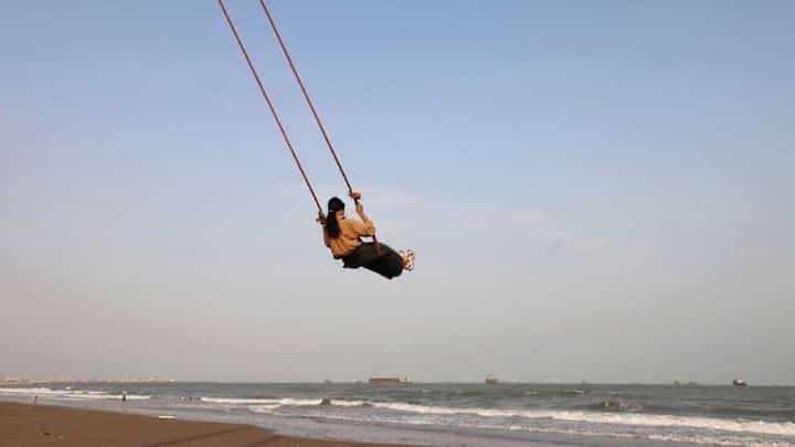 AN Iranian enjoys a swing erected along the seashore, as vessels are seen in the Strait of Hormuz off the port city of Bandar Abbas, in southern Iran on 10 August 2026.