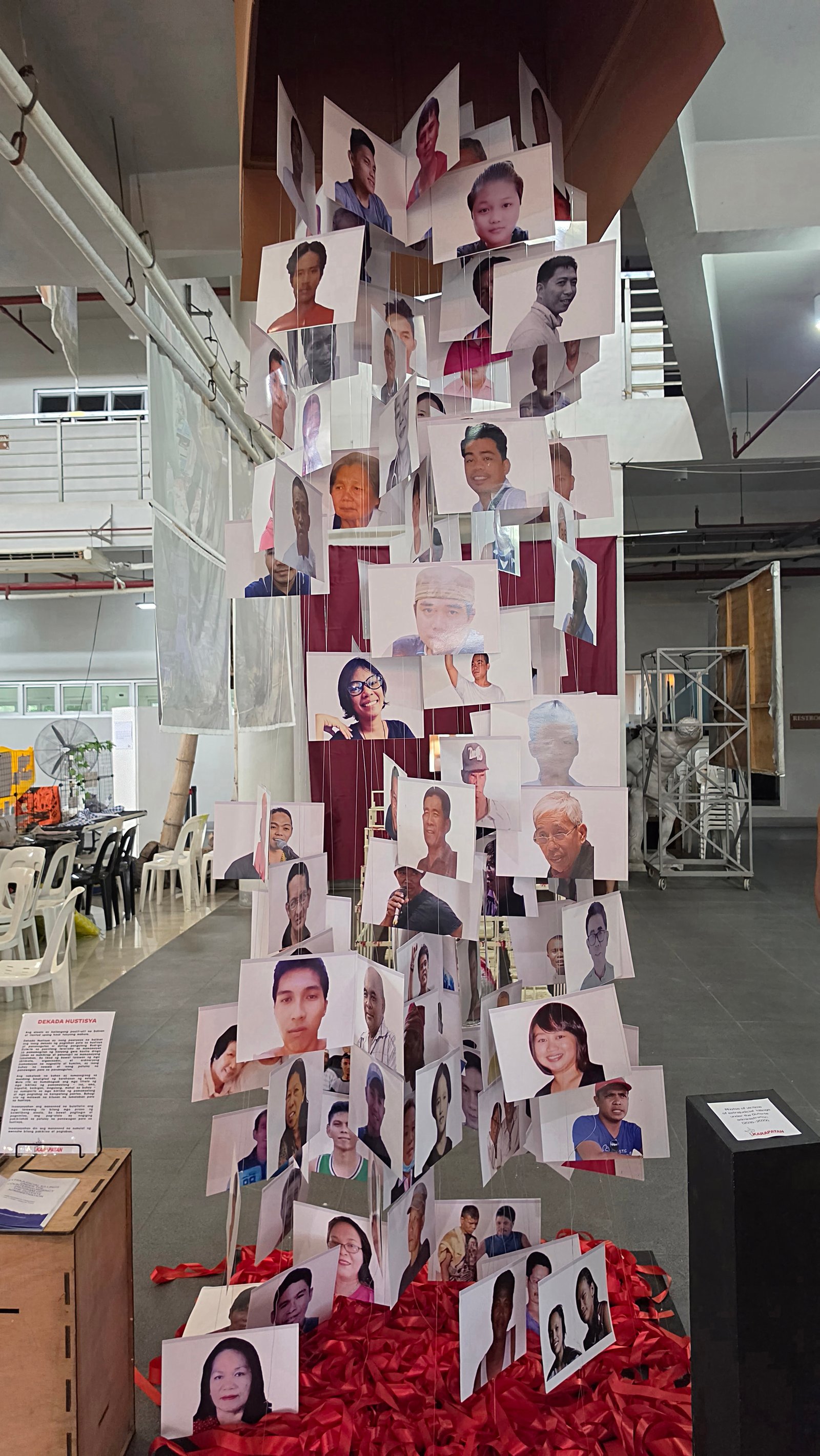 Portraits of extrajudicial-killing victims hang in a towering memorial installation, restoring individual faces and lives to the overwhelming death toll.