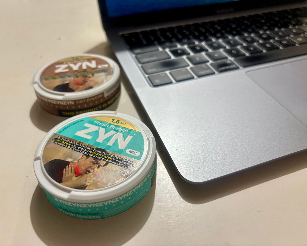 ZYN nicotine pouches sit beside a laptop.