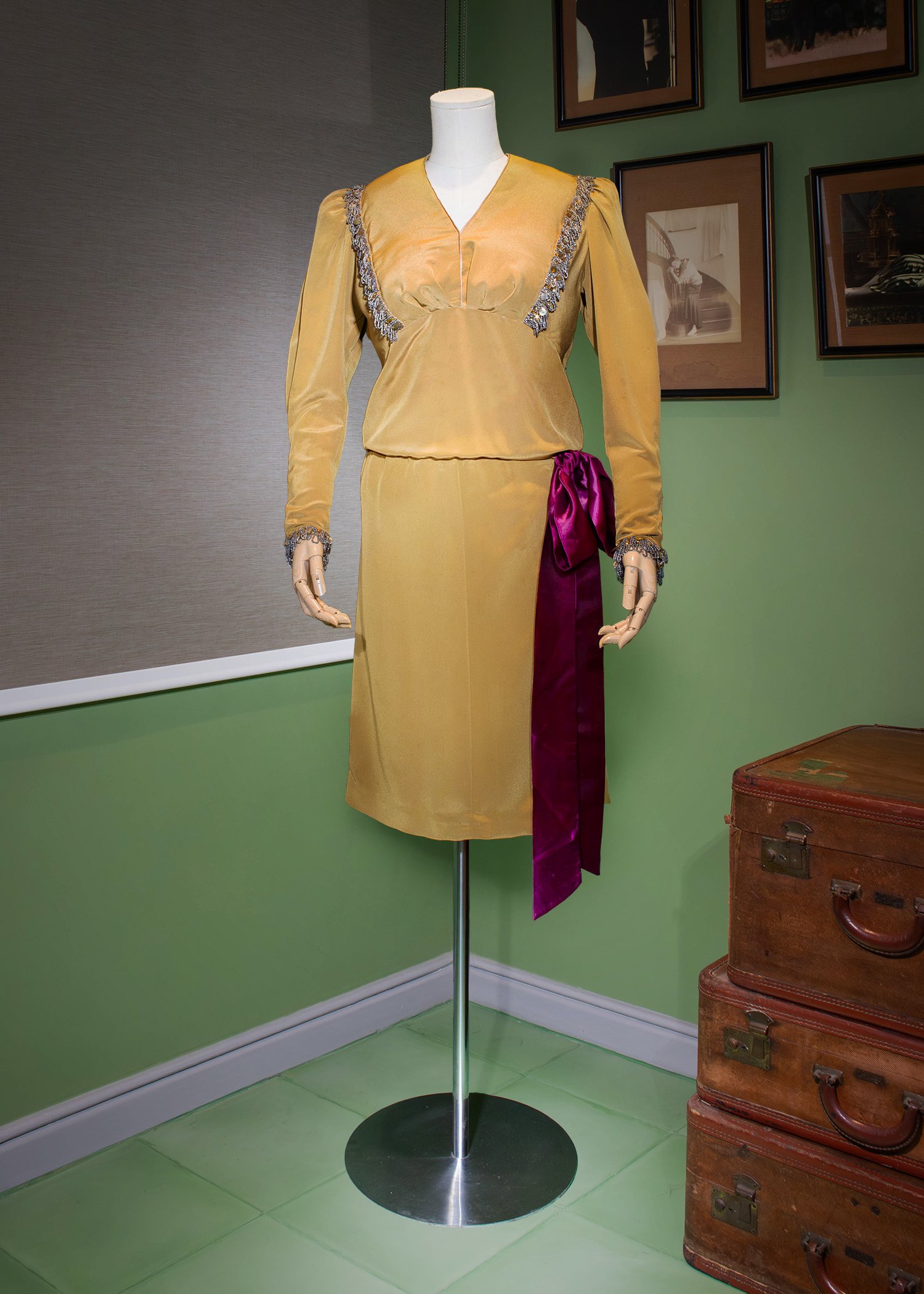 Mustard-yellow crepe blouson dress embellished with grey beadwork, featuring
gathered puff sleeves with beaded wide cuffs.
and accented with a purple satin ribbon