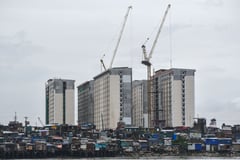 High rise building looms an informal settlement amid PH Triillion Debt