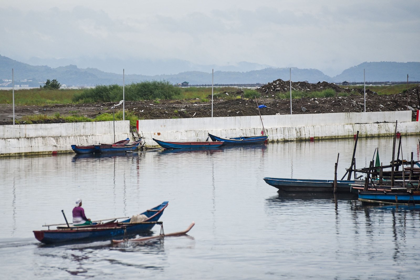 Fisherman Eddy Casin, 46, stands near his makeshift home beside the Lakeshore Complex in Taguig City on 5 September. Casin said the nearby reclamation project has hurt his livelihood, making it harder to earn from fishing and meet his daily needs. | Zedrich Xylak Madrid